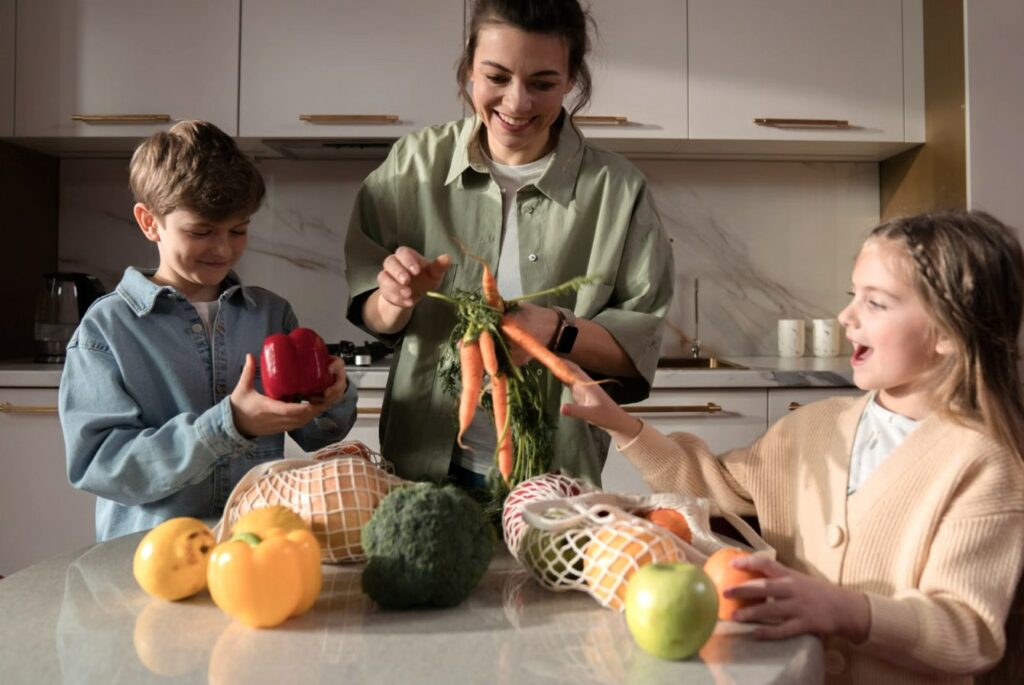 Maman préparant des légumes frais avec ses deux enfants dans une cuisine lumineuse