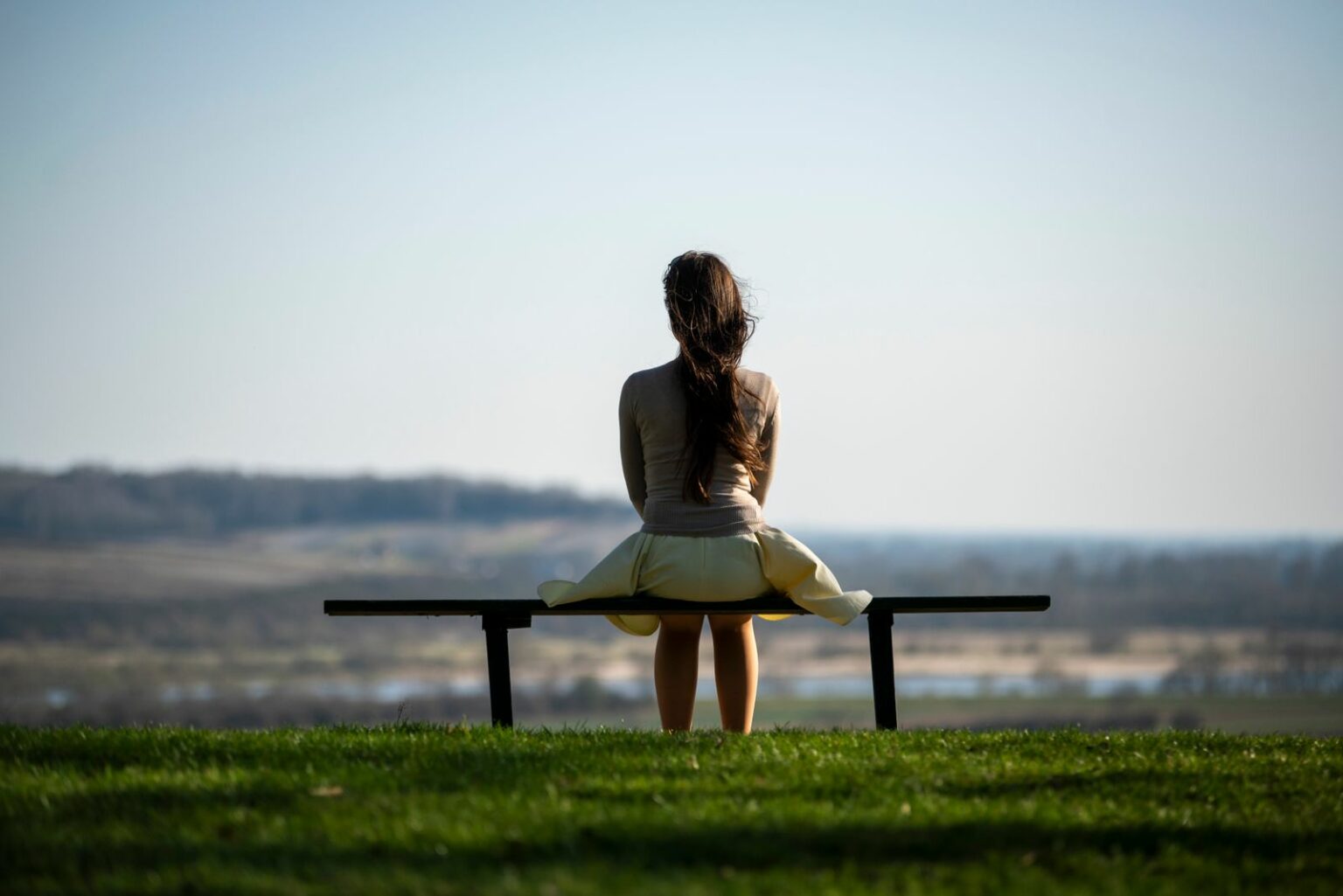 Femme assise sur un banc face à la mer, moment de réflexion à la quarantaine
