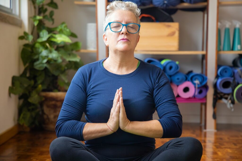 Femme aux cheveux gris en méditation, prendre soin de son humeur en périménopause